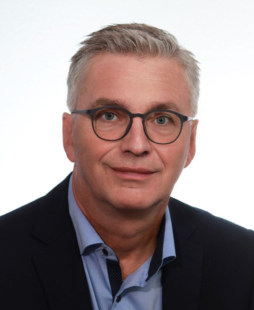 Porträt von Dr. Peter Geisler in legerer Business-Casual Kleidung vor einem hellen, neutralen Hintergrund – das Bild strahlt sympathische, authentische Professionalität und langjährige Erfahrung im Aftersales Service Management aus.
